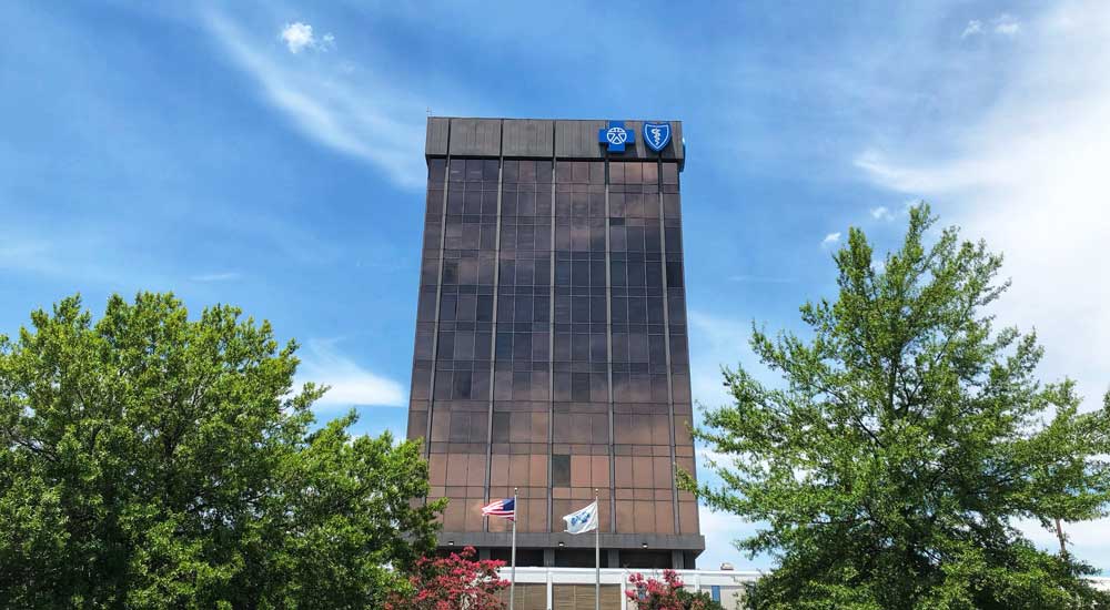 Blue Cross tower building with blue sky and trees