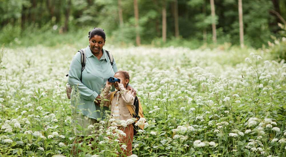 Woman and child standing in field with binoculars 