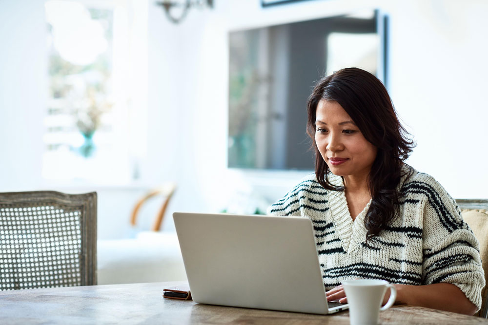 woman sitting at table looking at laptop